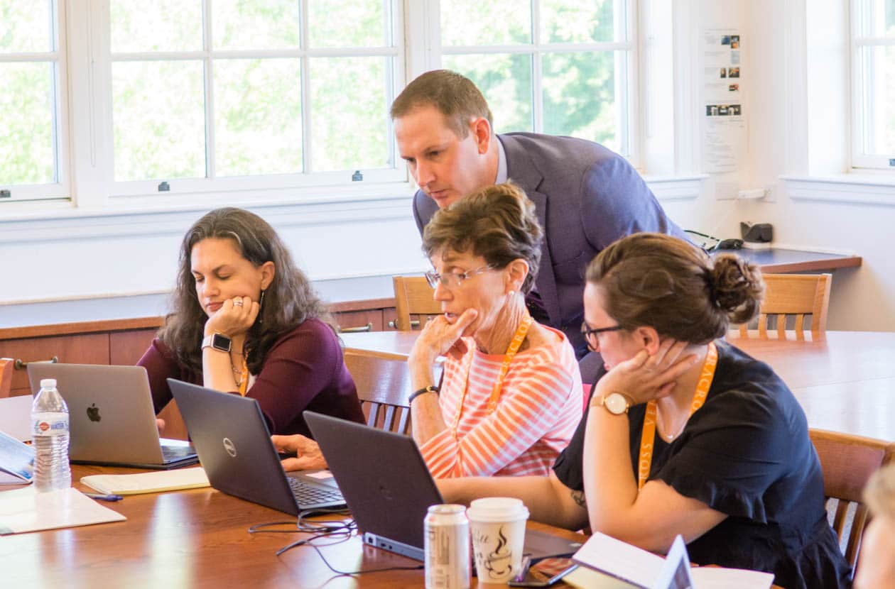 Teachers at a conference table looking at laptops