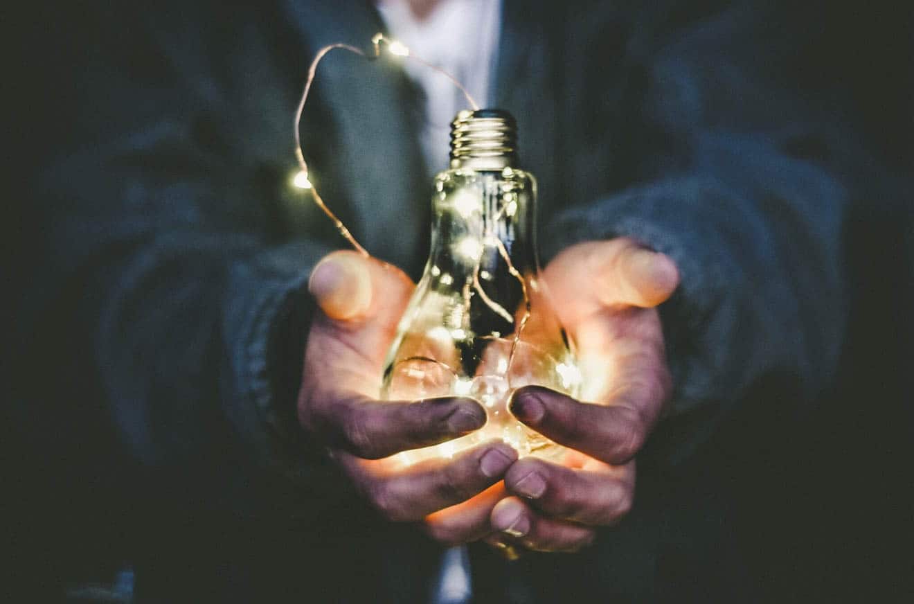 Person holding a lightbulb in their hands