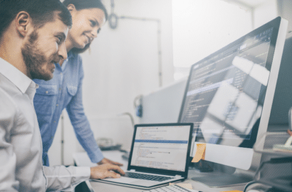 Image of two people looking at computer screens and smiling