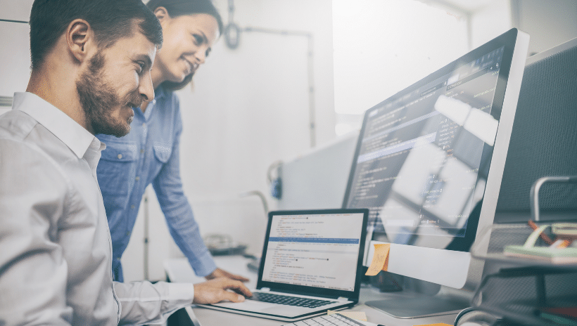 Image of two people looking at computer screens and smiling