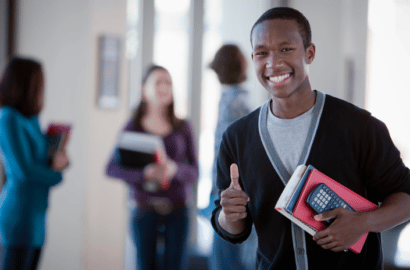 Private school student giving a thumbs up in the hallway