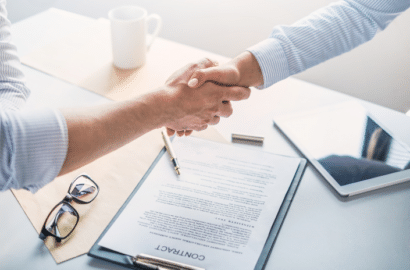 Two people shaking hands over a contract during the software evaluation process