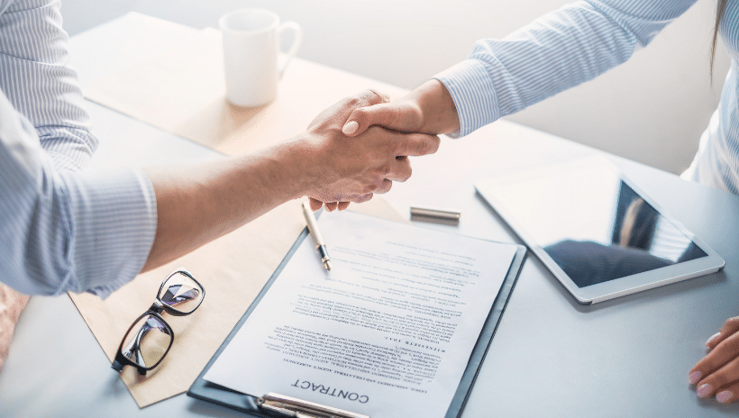 Two people shaking hands over a contract during the software evaluation process